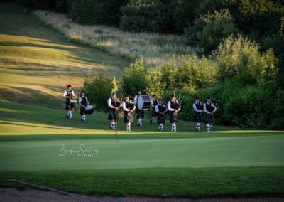 Dudelsackspieler in traditioneller Kleidung auf dem Golfplatz.